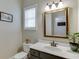 Cozy half-bathroom showcasing neutral colors, framed mirror, and natural light from a window at 457 Skiles Ct, Suwanee, GA 30024