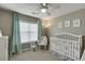 Cozy bedroom features a window with curtains, chair and a white crib at 457 Skiles Ct, Suwanee, GA 30024