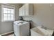 Functional laundry room with a modern washer and dryer, sink, and storage cabinets at 457 Skiles Ct, Suwanee, GA 30024