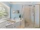 Bathroom features a soaking tub and a shower separated by a glass door with bright natural light from the window at 120 Ashewoode Downs Ln, Alpharetta, GA 30005