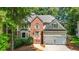 Charming two-story home featuring a brick facade, two-car garage, and lush landscaping at 120 Ashewoode Downs Ln, Alpharetta, GA 30005