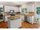 Well-lit kitchen featuring white cabinets, granite countertops, stainless steel appliances, and hardwood floors at 120 Ashewoode Downs Ln, Alpharetta, GA 30005