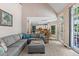 Open living room with gray sectional, ottoman, and views of the kitchen and dining areas at 120 Ashewoode Downs Ln, Alpharetta, GA 30005