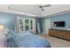 Bright primary bedroom featuring tray ceiling, with a view of the windows and a dresser with a TV at 120 Ashewoode Downs Ln, Alpharetta, GA 30005