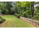 Beautiful backyard featuring a lush lawn, mature trees, and a classic wooden fence near the water at 2030 Darien Park Dr, Roswell, GA 30076