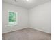 A bright, carpeted bedroom featuring a window with blinds and neutral walls at 261 Mahone Dr, Lilburn, GA 30047