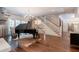 Elegant living room with hardwood floors, grand piano, chandelier, and staircase with white risers and wooden handrail at 101 Morgan Ln, Canton, GA 30115