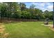 Expansive backyard featuring mature trees, a wooden fence, and a patio with an outdoor table and chairs at 4275 Hunters Walk Way, Cumming, GA 30028