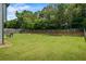 Expansive backyard with lush green grass, a wooden fence, and a patio with an outdoor table and grill at 4275 Hunters Walk Way, Cumming, GA 30028