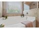 Close up of soaking tub and garden window in neutral-toned bathroom at 4275 Hunters Walk Way, Cumming, GA 30028
