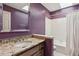 Well-lit bathroom with marble countertop vanity and shower-tub combo, features a decorative purple wall at 5195 Overbend Trl, Suwanee, GA 30024