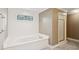 Elegant bathroom featuring a soaking tub, decorative window, walk-in shower and neutral decor at 5195 Overbend Trl, Suwanee, GA 30024