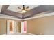 Bedroom showcasing tray ceiling detail with ceiling fan and open doors to ensuite bathroom at 5195 Overbend Trl, Suwanee, GA 30024