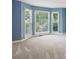 Bright bedroom with three-panel bay window offering wooded views and neutral carpeting at 5195 Overbend Trl, Suwanee, GA 30024