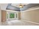 Bright bedroom featuring a bay window with wooded view, gray trey ceiling, and neutral carpet at 5195 Overbend Trl, Suwanee, GA 30024