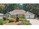 Charming brick home with a well-manicured lawn and a two-car garage nestled amongst mature trees at 5195 Overbend Trl, Suwanee, GA 30024