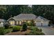 Charming brick home with a well-manicured lawn and a two-car garage nestled amongst mature trees at 5195 Overbend Trl, Suwanee, GA 30024