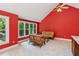 Bright living room with high ceilings, large windows, red walls, and wicker furniture at 5195 Overbend Trl, Suwanee, GA 30024