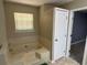 Bathroom with tiled tub and a window for natural light at 110 Stagecoach Trl, Stockbridge, GA 30281