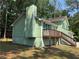 An exterior view of a light green home with a chimney and back deck at 110 Stagecoach Trl, Stockbridge, GA 30281