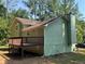 An exterior back view of a light green home with a chimney and back deck at 110 Stagecoach Trl, Stockbridge, GA 30281