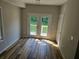Bedroom featuring wood floors and french doors to a private deck with views of surrounding greenery at 3120 Chattahoochee Rd, Cumming, GA 30041