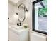 Modern powder room featuring a sleek vanity, an oval mirror with sconces, a large window with a view, and neutral tiles at 6090 River Chase Cir, Atlanta, GA 30328
