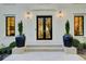 Elegant front entrance with black double doors, modern lighting, and potted greenery on a white brick facade at 6090 River Chase Cir, Atlanta, GA 30328