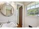 Well-lit bathroom with a round mirror over a modern sink, bright window, and wood floor at 3089 Ranlo Dr, Atlanta, GA 30340