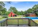 A backyard view featuring a pool, barn, and secondary outbuilding, surrounded by lush trees, as seen from the deck at 205 Cobb St, Palmetto, GA 30268