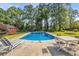 In-ground swimming pool is surrounded by a concrete patio furnished with lounge chairs and a table with chairs at 205 Cobb St, Palmetto, GA 30268