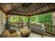 A covered back deck provides outdoor living space with a grill, seating, and wooded view at 4971 Fairhaven Ne Way, Roswell, GA 30075