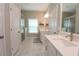 Bright bathroom with double vanity sinks, white cabinetry, and a glass enclosed shower and marble flooring at 5714 Pickens Garden Ln, Powder Springs, GA 30127
