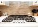 Close-up of a modern gas range with stainless steel finish, situated beneath a tile backsplash at 5714 Pickens Garden Ln, Powder Springs, GA 30127