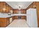 Kitchen with wood cabinets, white appliances, and vinyl floors, creating a functional cooking space at 338 Patterson Rd, Lawrenceville, GA 30044