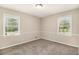 Bright bedroom featuring neutral colored carpet, light walls, and natural light from two windows at 41 Elder St, Fairburn, GA 30213