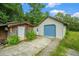 Garage and shed feature a blue roll-up door and mature plants at 1198 Old Mill Rd, Dallas, GA 30157