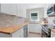 Well-lit kitchen featuring updated appliances, tile backsplash, and butcher block countertops at 2483 Hunting Valley Dr, Decatur, GA 30033