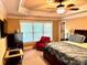 This is a primary bedroom with a decorative tray ceiling, windows, an accent chair and an en-suite bathroom at 3310 Mcclure Woods Ct, Duluth, GA 30096