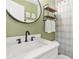 Bathroom featuring green walls, a black faucet, and a large circular mirror at 727 Holmes Nw St, Atlanta, GA 30318
