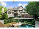 Elegant exterior featuring a three-car garage, white brick, and a stone chimney with a paved driveway and mature trees at 1525 Lockridge Dr, Cumming, GA 30041