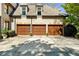 Three-car garage featuring wooden doors, brick facade, and ample parking space with a paver detail at 1525 Lockridge Dr, Cumming, GA 30041