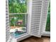 A lakeside view from a window showcases a pool and dock through white shutters at 1525 Lockridge Dr, Cumming, GA 30041