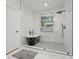 Bright bathroom featuring a sleek black soaking tub, glass shower, and modern fixtures against white marble tiling at 90 Mckown Rd, Fayetteville, GA 30214
