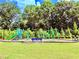 A colorful community playground is set on a grassy lawn with benches and mature trees at 5599 Wheeler Ridge Rd, Auburn, GA 30011