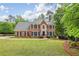 Stately two-story brick home featuring a well-manicured lawn and mature trees at 730 Mount Oglethorpe Trl, Alpharetta, GA 30022