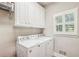Bright laundry room with white appliances, shuttered window, and plenty of storage at 730 Mount Oglethorpe Trl, Alpharetta, GA 30022