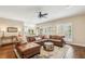 Open living room featuring a leather sectional sofa, ceiling fan, wood floors, and plantation shutters at 730 Mount Oglethorpe Trl, Alpharetta, GA 30022