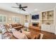 Spacious living room with a brick fireplace, built-in shelving, plantation shutters, and hardwood floors at 730 Mount Oglethorpe Trl, Alpharetta, GA 30022