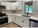 Modern kitchen featuring white cabinets, stainless steel appliances, marble backsplash, and a sink overlooking the backyard at 7562 Asbury Manor Dr, Lithonia, GA 30014